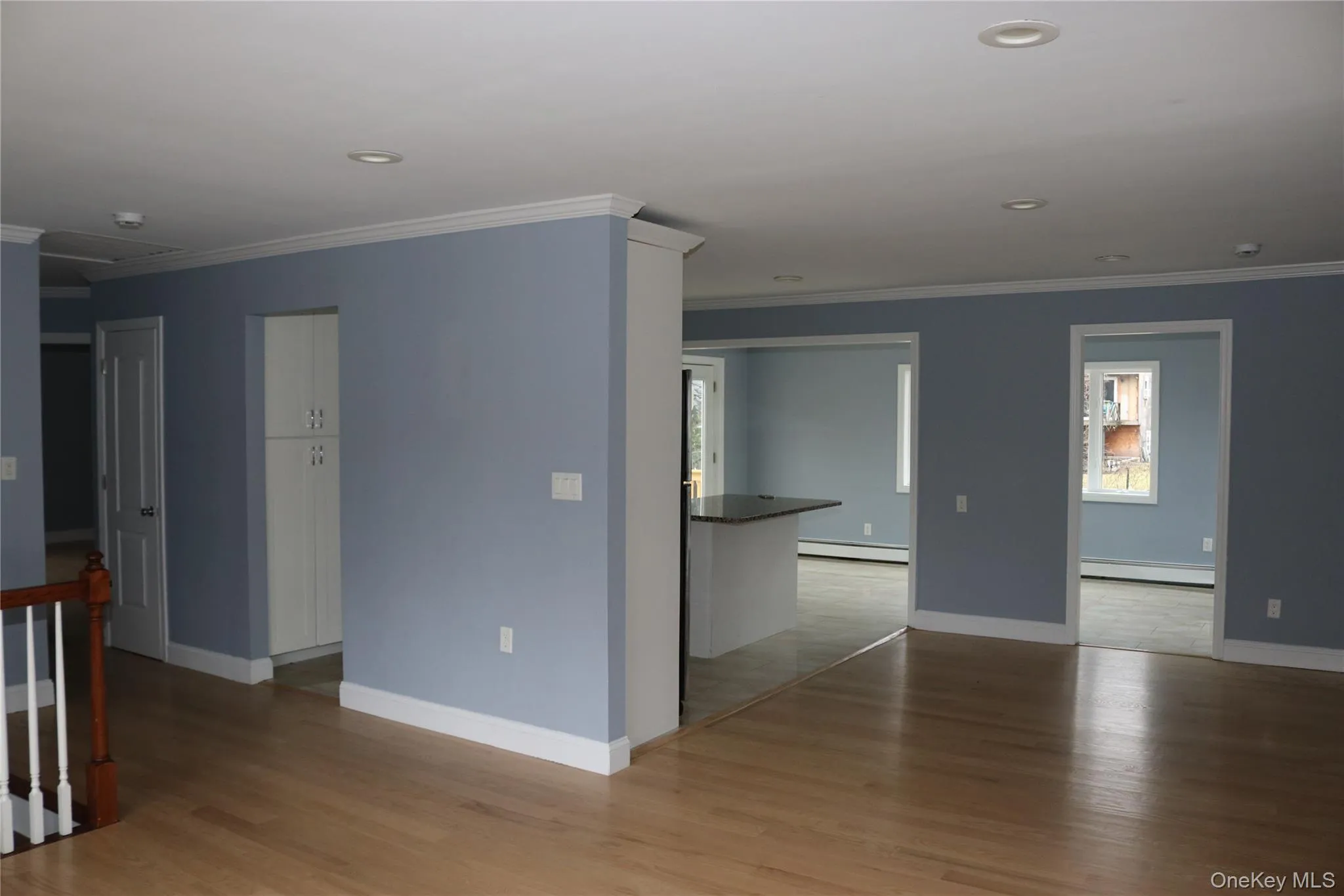 Empty room featuring light wood-type flooring, ornamental molding, baseboard heating, and recessed lighting Empty room featuring light wood-type flooring, ornamental molding, baseboard heating, and recessed lighting