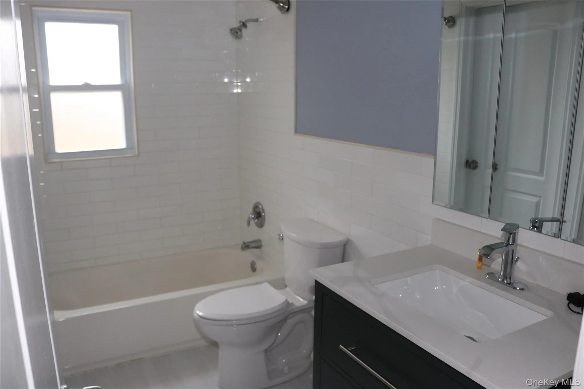 Main Bathroom featuring vanity, tile walls, and washtub / shower combination Main Bathroom featuring vanity, tile walls, and washtub / shower combination