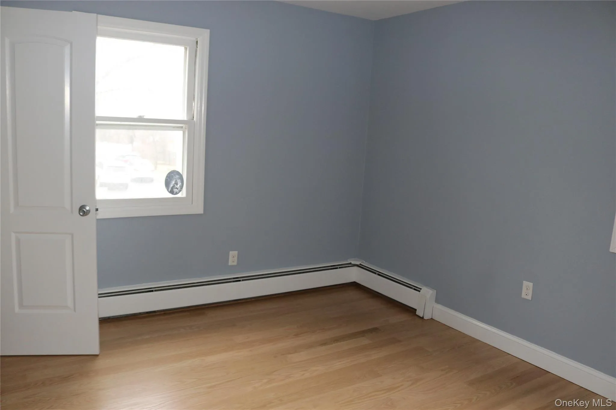Bedroom featuring light wood-style flooring and a baseboard heating unit Bedroom featuring light wood-style flooring and a baseboard heating unit