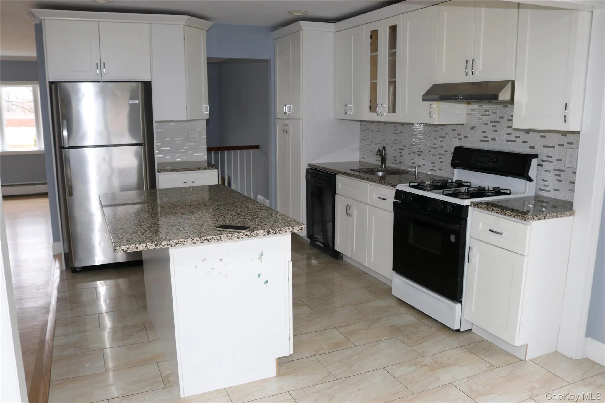 Kitchen with gas range, light stone counters, freestanding refrigerator, and tasteful backsplash Kitchen with gas range, light stone counters, freestanding refrigerator, and tasteful backsplash