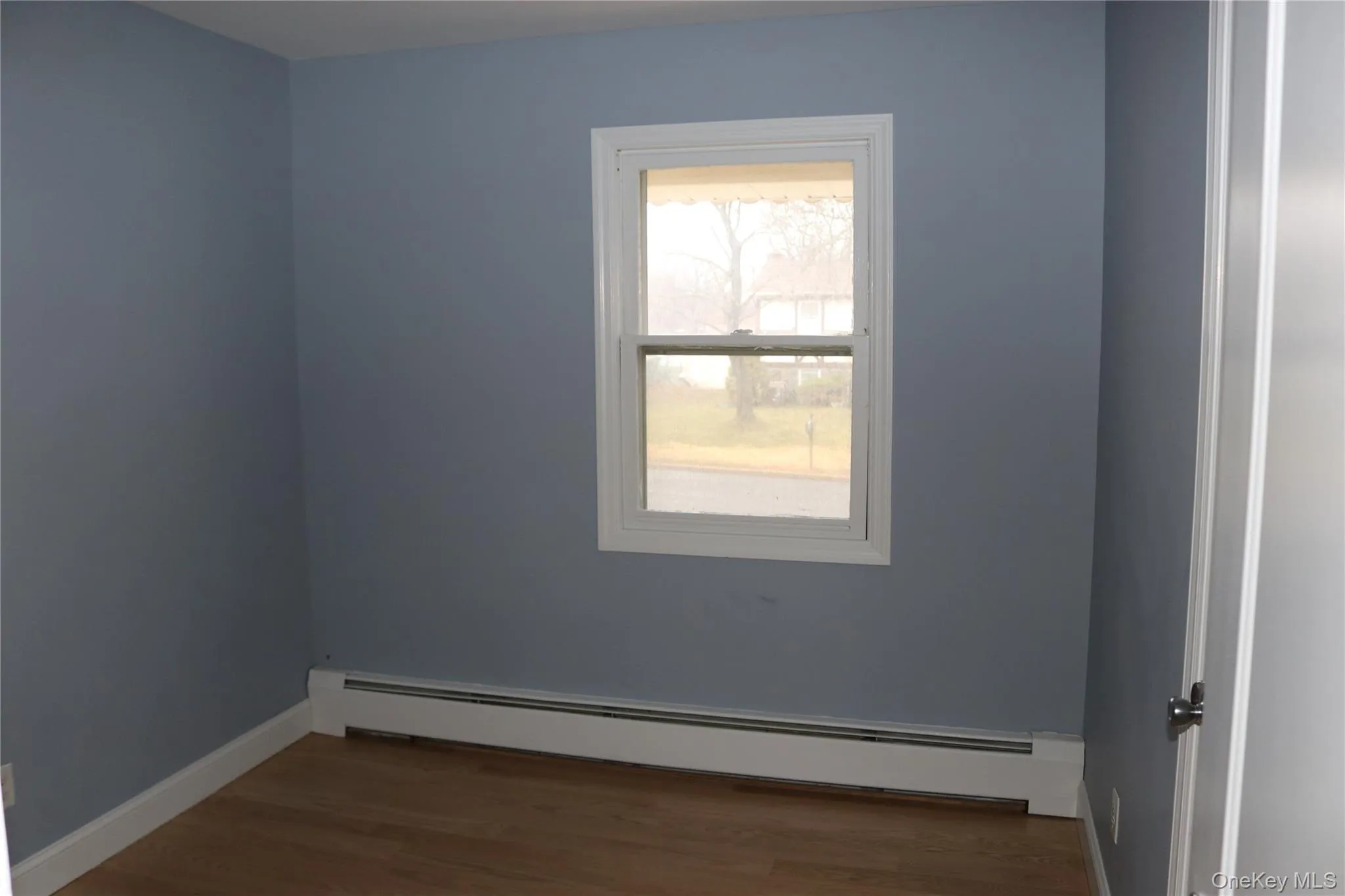 Bedroom featuring a baseboard radiator and dark wood-type flooring Bedroom featuring a baseboard radiator and dark wood-type flooring
