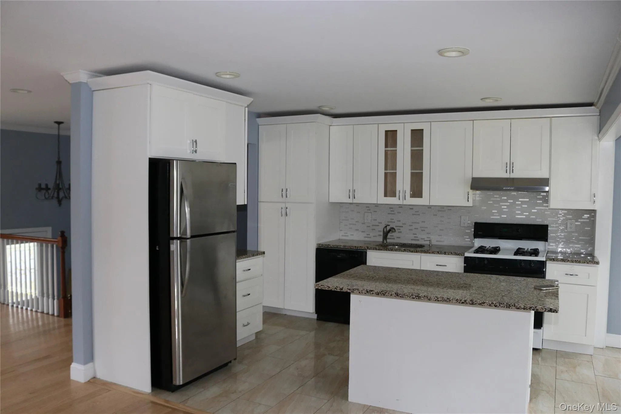 Kitchen with freestanding refrigerator, dark stone counters, white cabinets, gas range oven, and crown molding Kitchen with freestanding refrigerator, dark stone counters, white cabinets, gas range oven, and crown molding