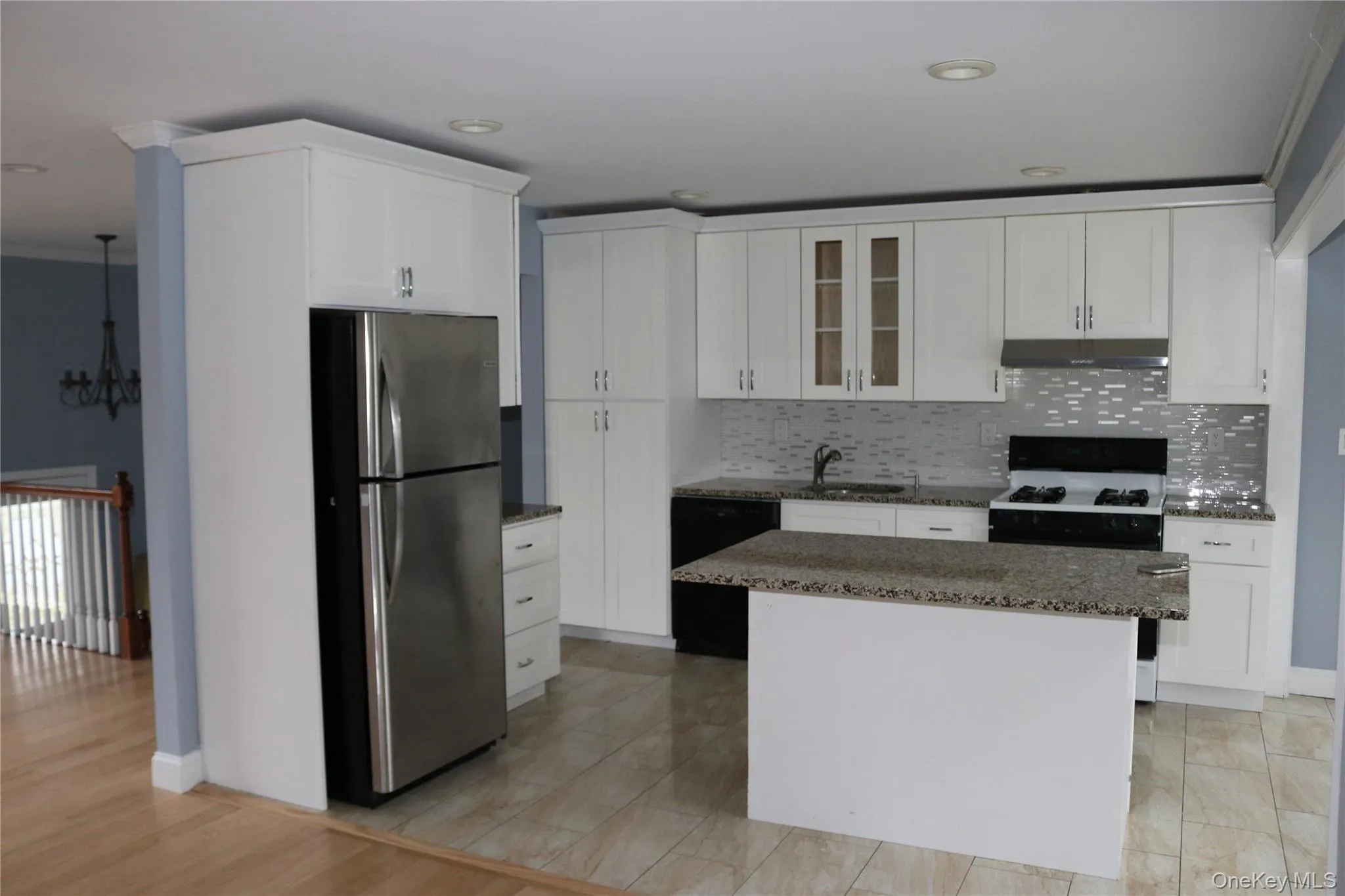 Kitchen featuring freestanding refrigerator, white cabinetry, gas stove, dark stone counters, and ornamental molding Kitchen featuring freestanding refrigerator, white cabinetry, gas stove, dark stone counters, and ornamental molding