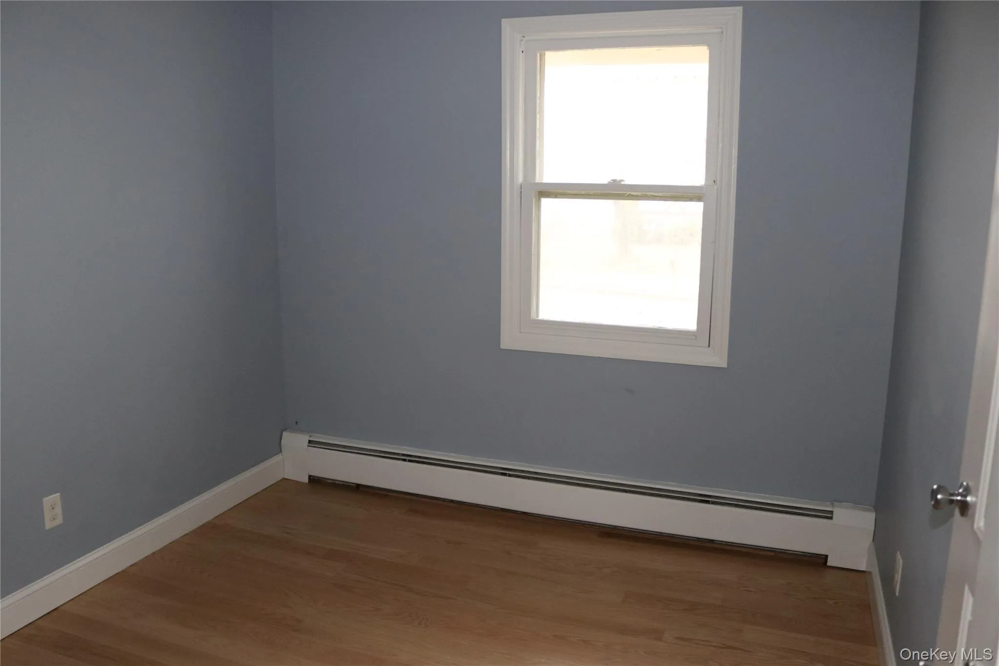 Bedroom featuring a baseboard heating unit and wood finished floors Bedroom featuring a baseboard heating unit and wood finished floors