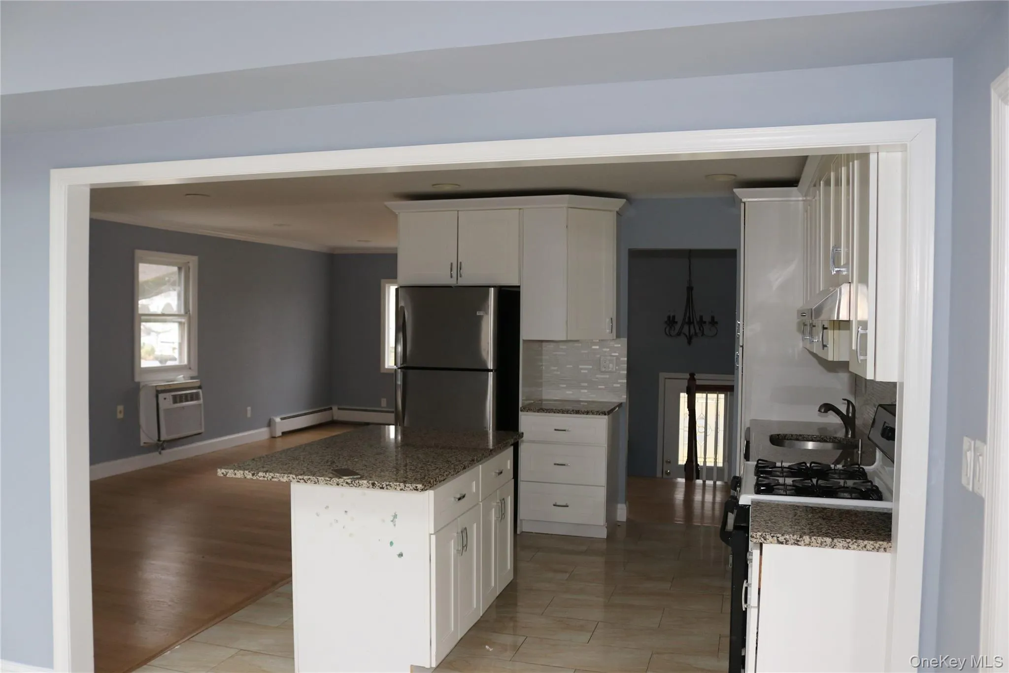 Kitchen with gas range, white cabinets, light stone countertops, freestanding refrigerator, and ornamental molding Kitchen with gas range, white cabinets, light stone countertops, freestanding refrigerator, and ornamental molding