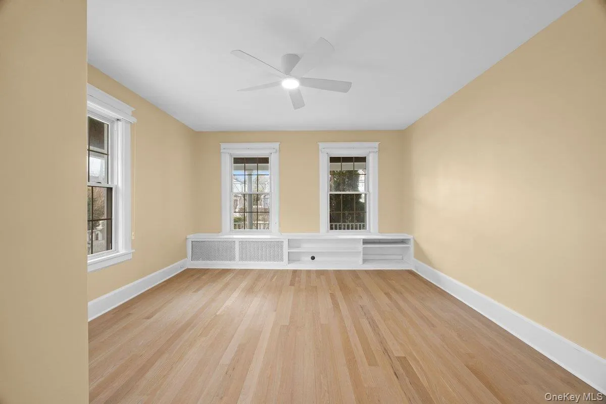 Bedroom #1 with hardwood flooring, radiator, ceiling fan, and plenty of natural light Bedroom #1 with hardwood flooring, radiator, ceiling fan, and plenty of natural light