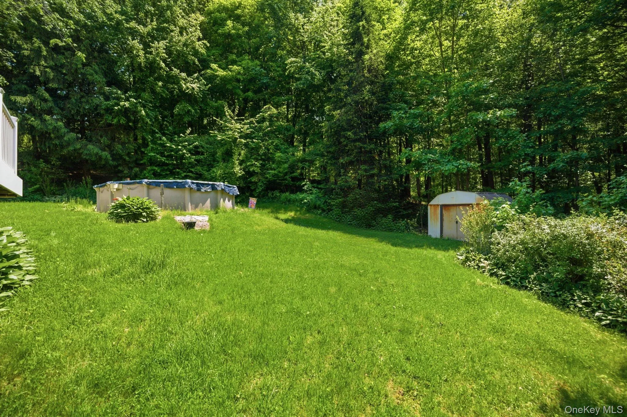 The level backyard offers a pool, a storage shed, and open lawn bordered by woods for added seclusion. The level backyard offers a pool, a storage shed, and open lawn bordered by woods for added seclusion.