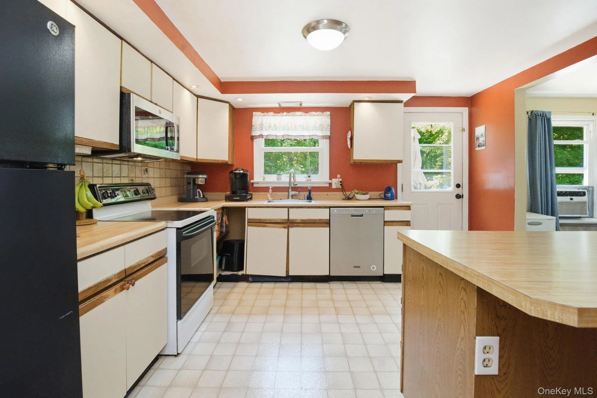 The eat-in kitchen offers generous cabinetry, a window over the sink overlooking the trees, and a side door for easy access to the deck. The eat-in kitchen offers generous cabinetry, a window over the sink overlooking the trees, and a side door for easy access to the deck.