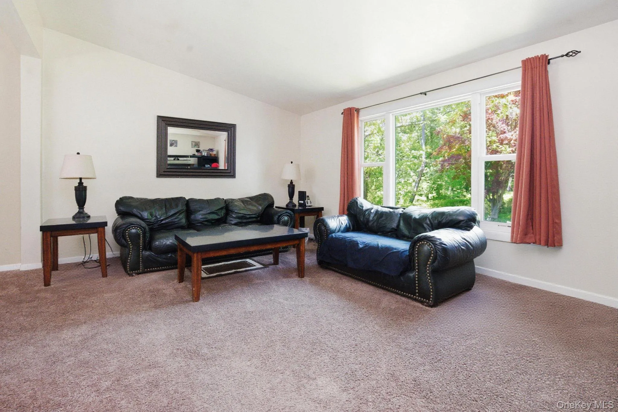 The living room is anchored by a wide picture window framing the green, wooded views that surround the property. The living room is anchored by a wide picture window framing the green, wooded views that surround the property.
