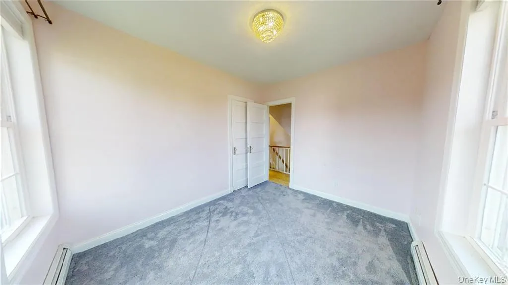 Carpeted spare room with plenty of natural light and a baseboard heating unit Carpeted spare room with plenty of natural light and a baseboard heating unit