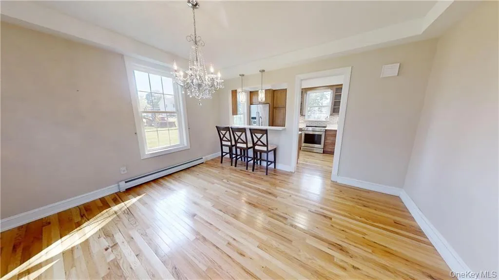 Dining room featuring a baseboard heating unit, light wood-style floors, healthy amount of natural light, and a chandelier Dining room featuring a baseboard heating unit, light wood-style floors, healthy amount of natural light, and a chandelier