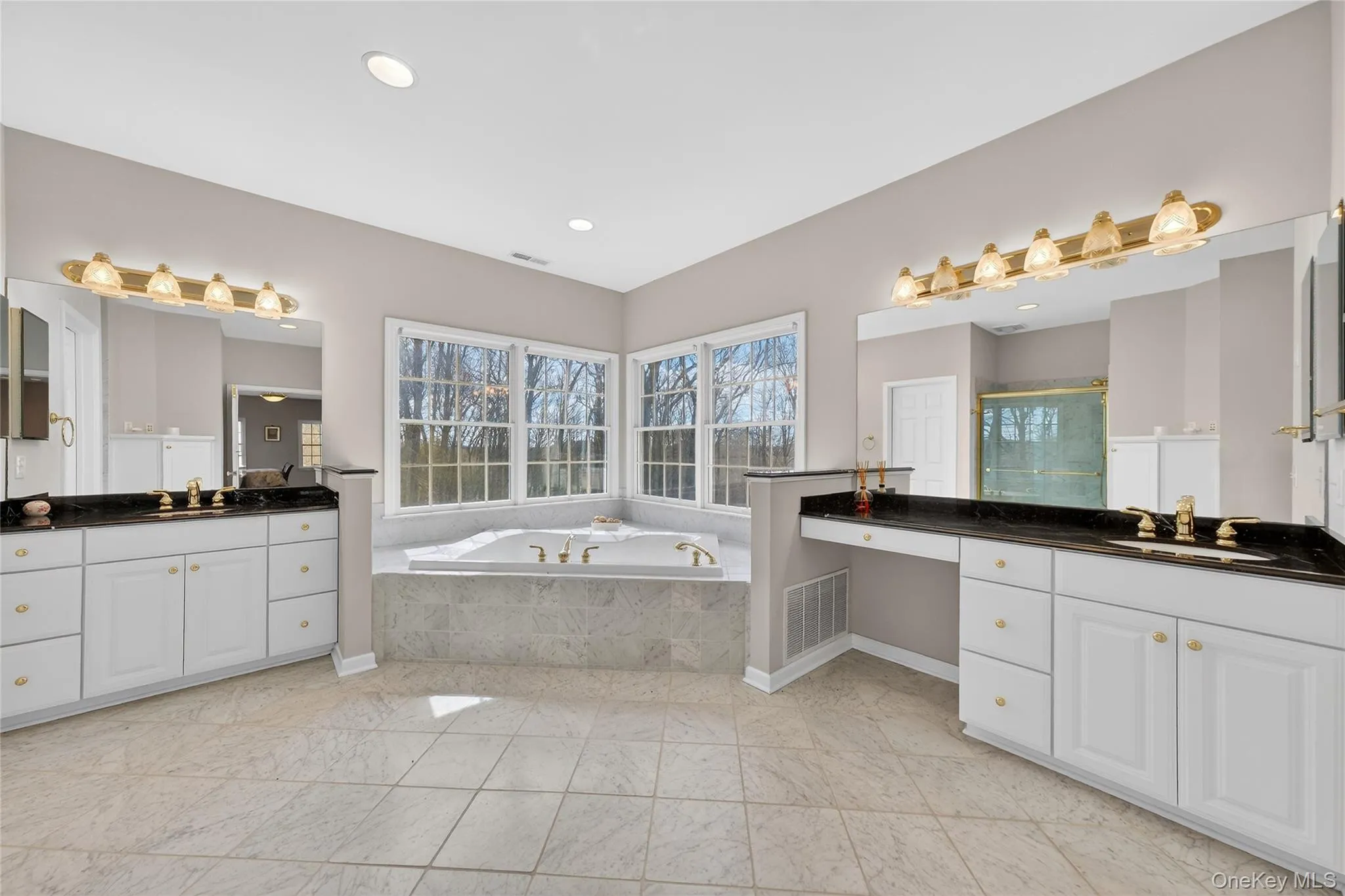 The primary bathroom boasts a Jacuzzi tub, stall shower, and two separate vanities. The primary bathroom boasts a Jacuzzi tub, stall shower, and two separate vanities.