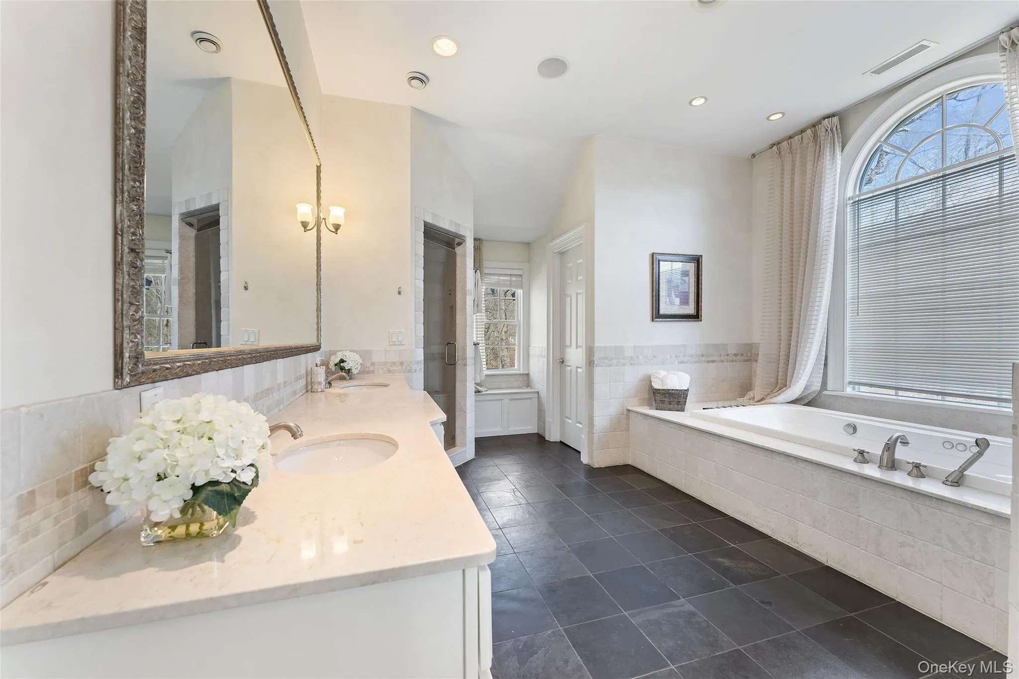 Primary en suite spa bathroom with soaking tub, glass shower, double vanity, and private water closet Primary en suite spa bathroom with soaking tub, glass shower, double vanity, and private water closet