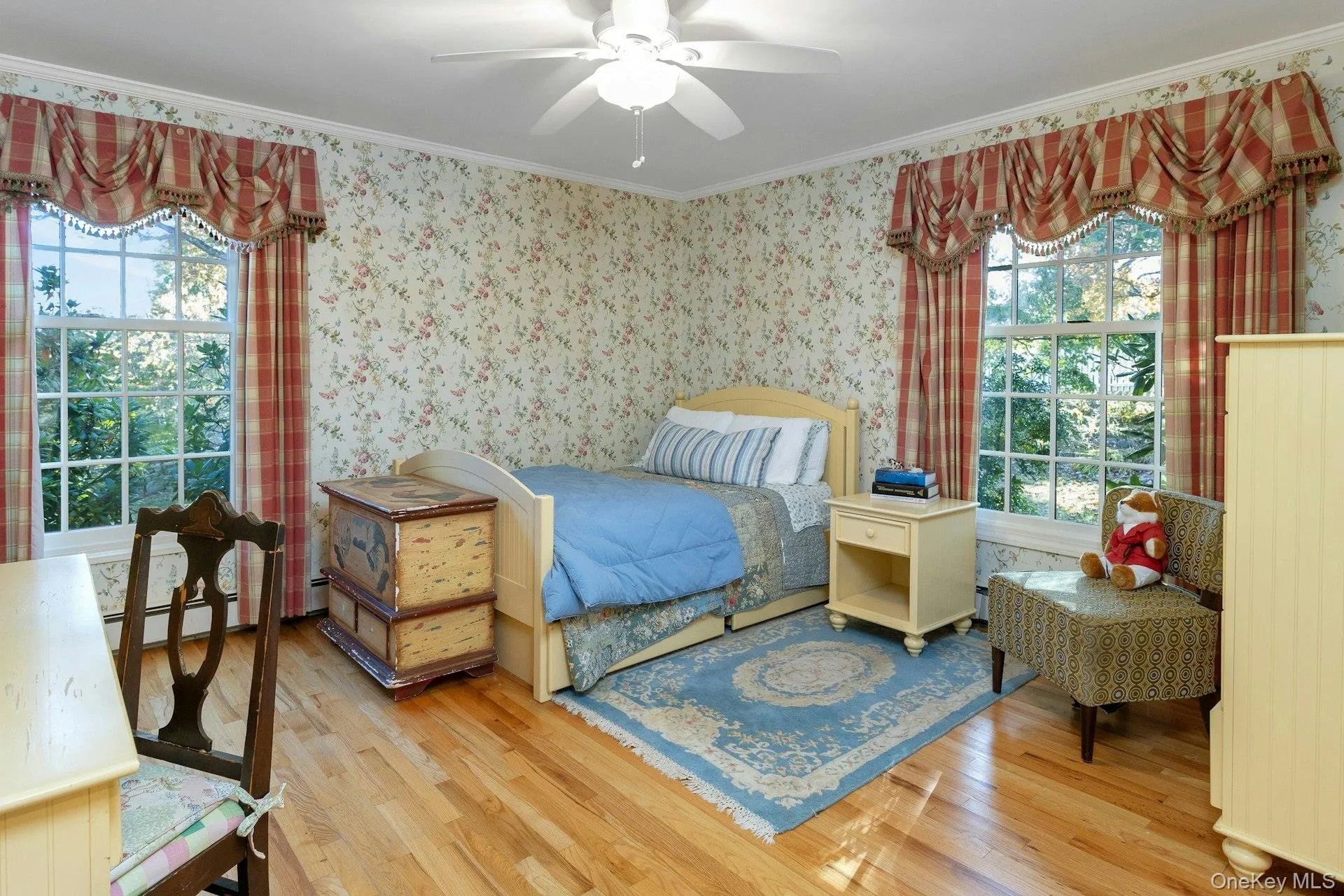 Bedroom featuring crown molding, light wood-type flooring, wallpapered walls, ceiling fan, and a baseboard radiator Bedroom featuring crown molding, light wood-type flooring, wallpapered walls, ceiling fan, and a baseboard radiator