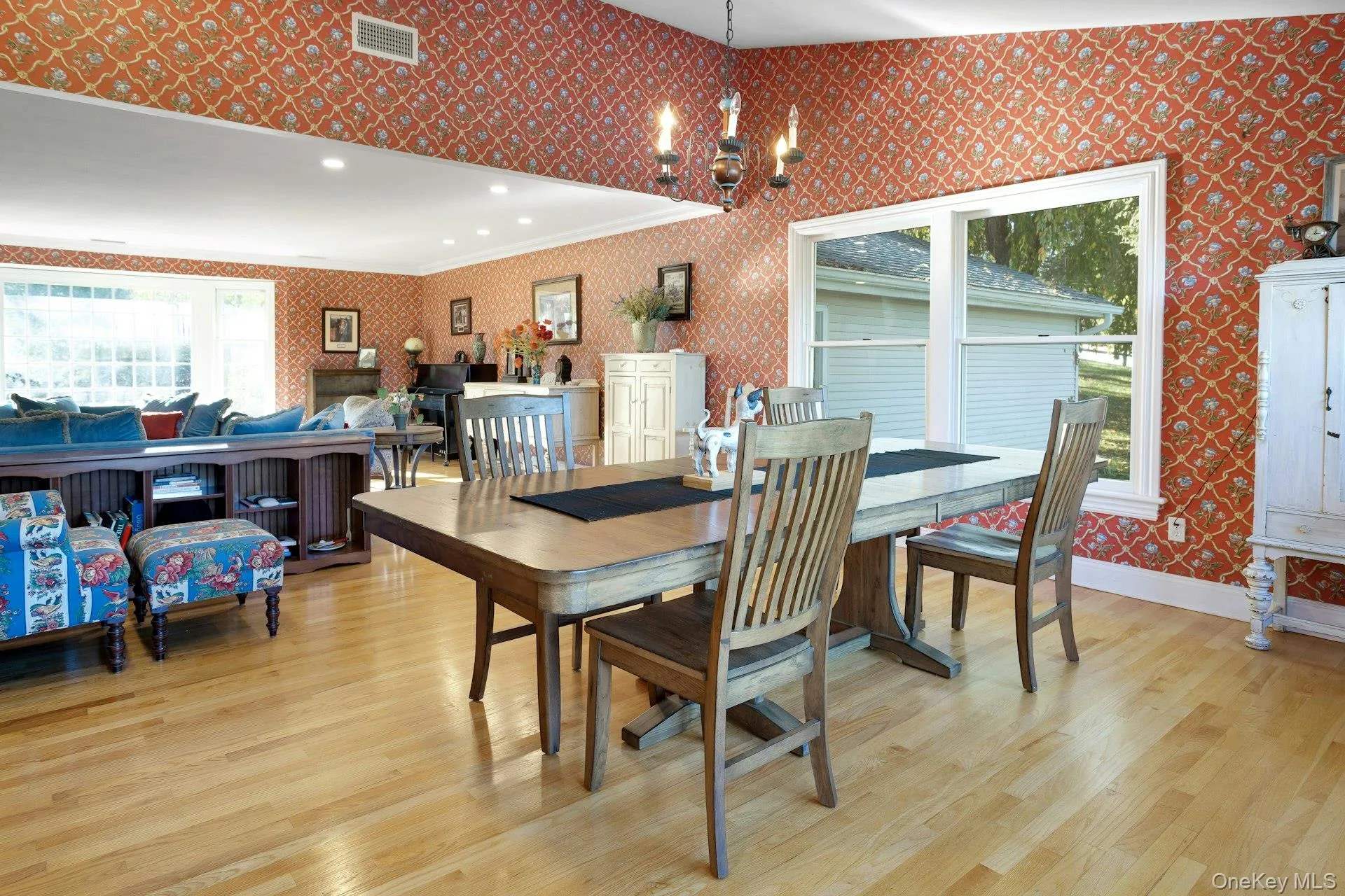 Dining space featuring wallpapered walls, light wood-type flooring, ornamental molding, and a chandelier Dining space featuring wallpapered walls, light wood-type flooring, ornamental molding, and a chandelier