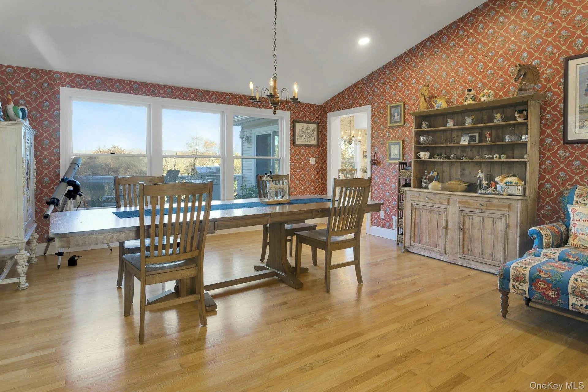 Dining room with wallpapered walls, light wood-style floors, a chandelier, vaulted ceiling, and recessed lighting Dining room with wallpapered walls, light wood-style floors, a chandelier, vaulted ceiling, and recessed lighting