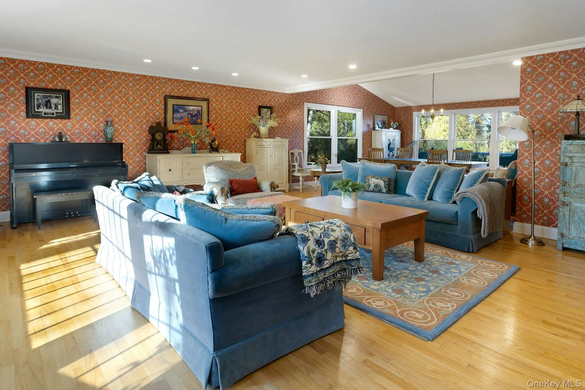 Living area featuring wallpapered walls, ornamental molding, light wood finished floors, recessed lighting, and lofted ceiling Living area featuring wallpapered walls, ornamental molding, light wood finished floors, recessed lighting, and lofted ceiling