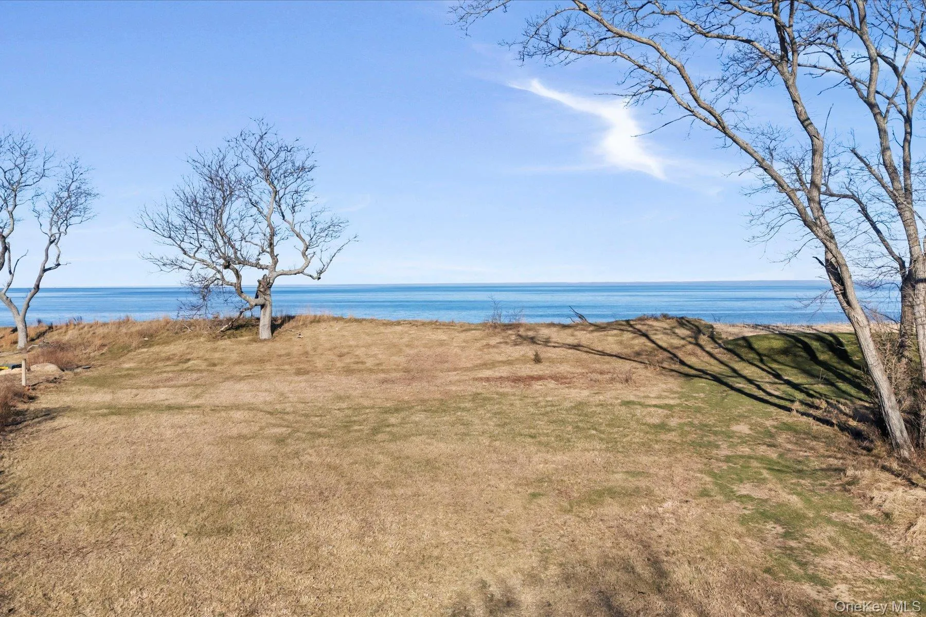 Expansive open lawn on the bluff with unobstructed water views, framed by mature trees and wide blue-sky horizons along the shoreline. Expansive open lawn on the bluff with unobstructed water views, framed by mature trees and wide blue-sky horizons along the shoreline.