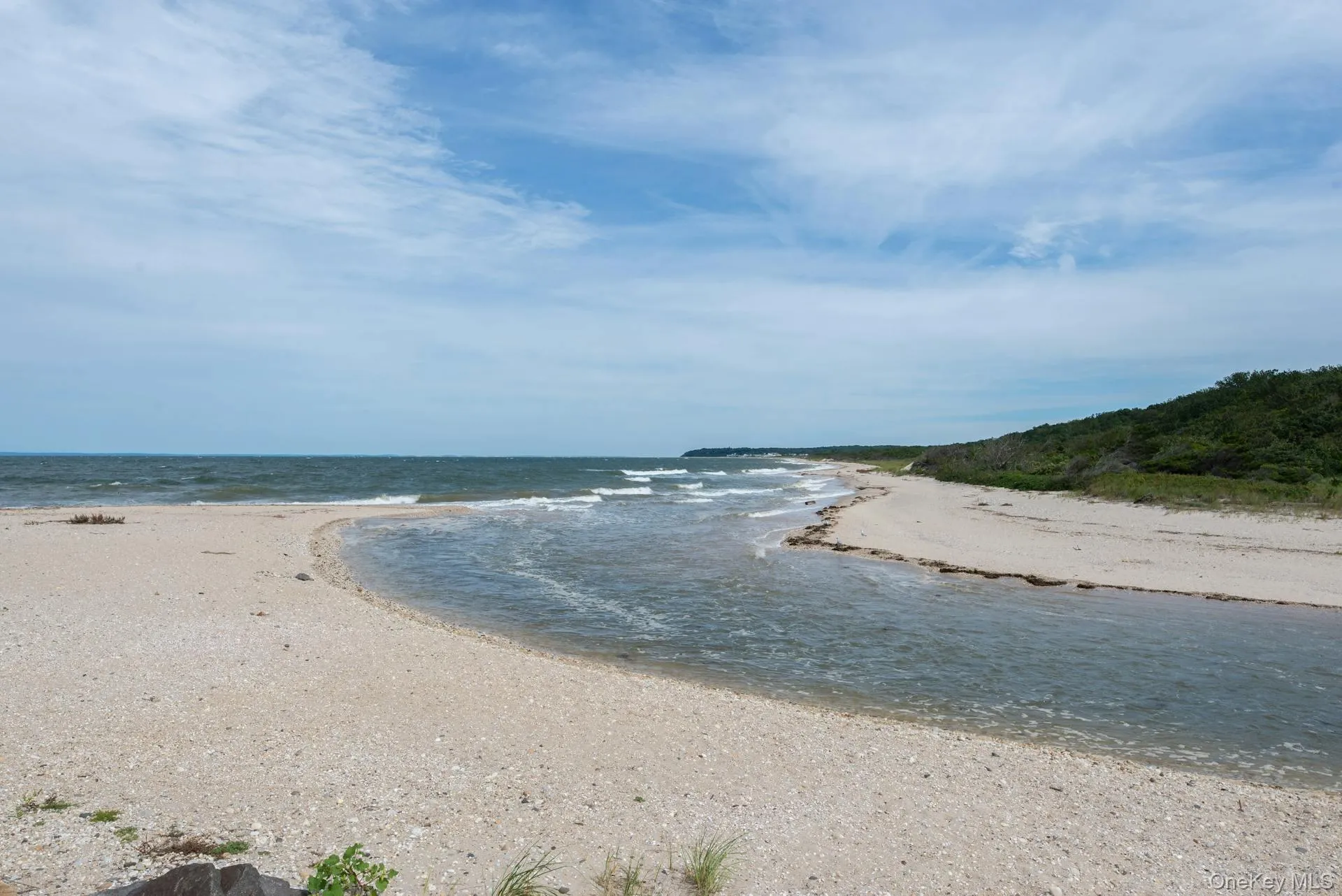 Scenic shoreline view with sandy beach, gentle waves, and a natural coastal inlet, showcasing the unspoiled waterfront setting and expansive horizon beyond Scenic shoreline view with sandy beach, gentle waves, and a natural coastal inlet, showcasing the unspoiled waterfront setting and expansive horizon beyond