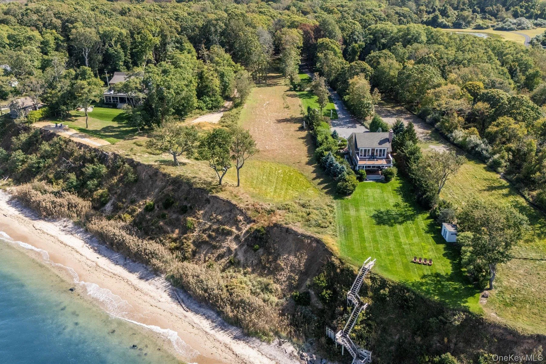 Aerial view highlighting the property's prime waterfront position along the bluff, with expansive shoreline frontage, open lawn areas, and scenic surroundings along the North Fork coast Aerial view highlighting the property's prime waterfront position along the bluff, with expansive shoreline frontage, open lawn areas, and scenic surroundings along the North Fork coast