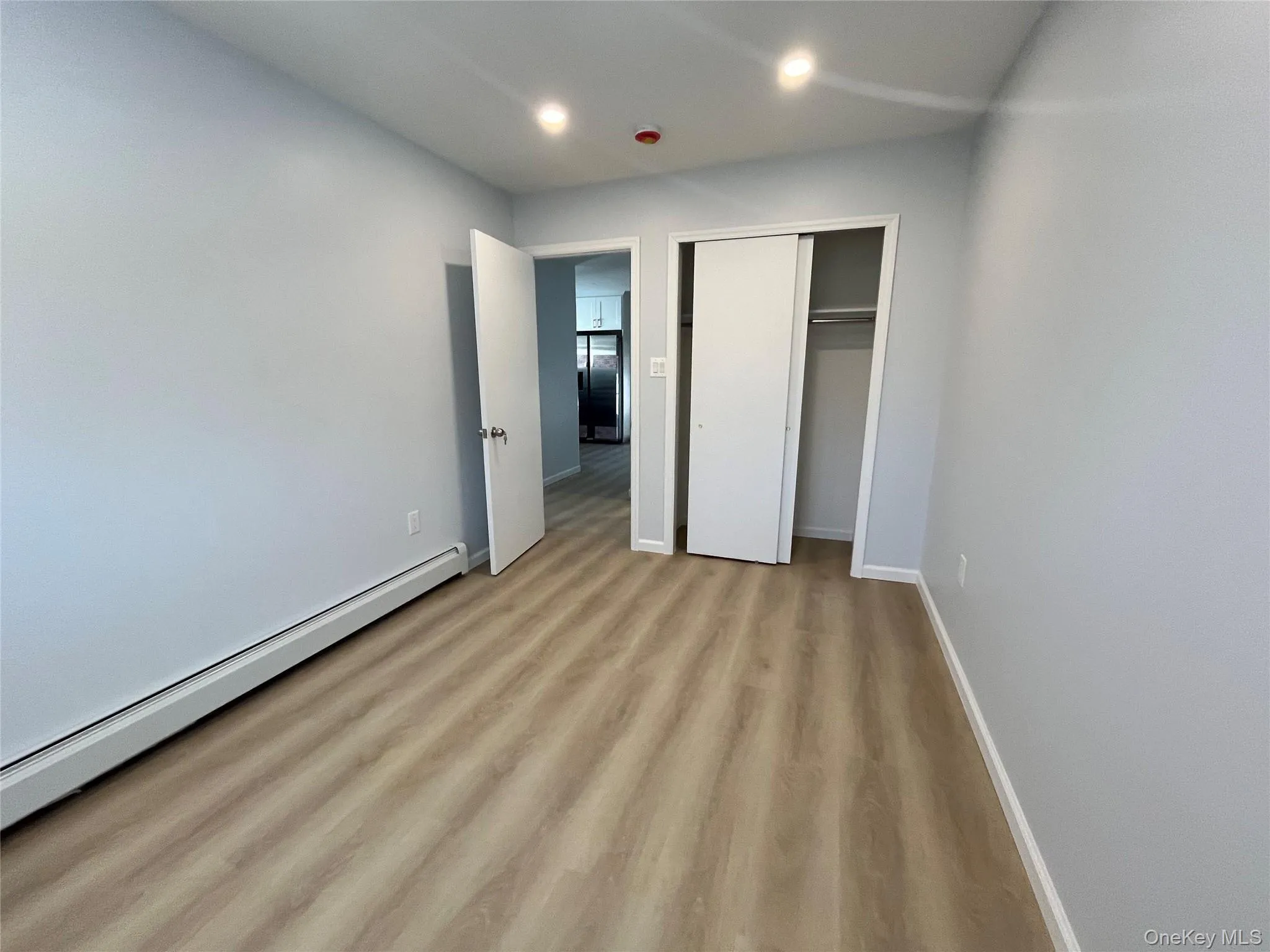 Bedroom with baseboard heating, light wood-style flooring, a closet, recessed lighting. Bedroom with baseboard heating, light wood-style flooring, a closet, recessed lighting.