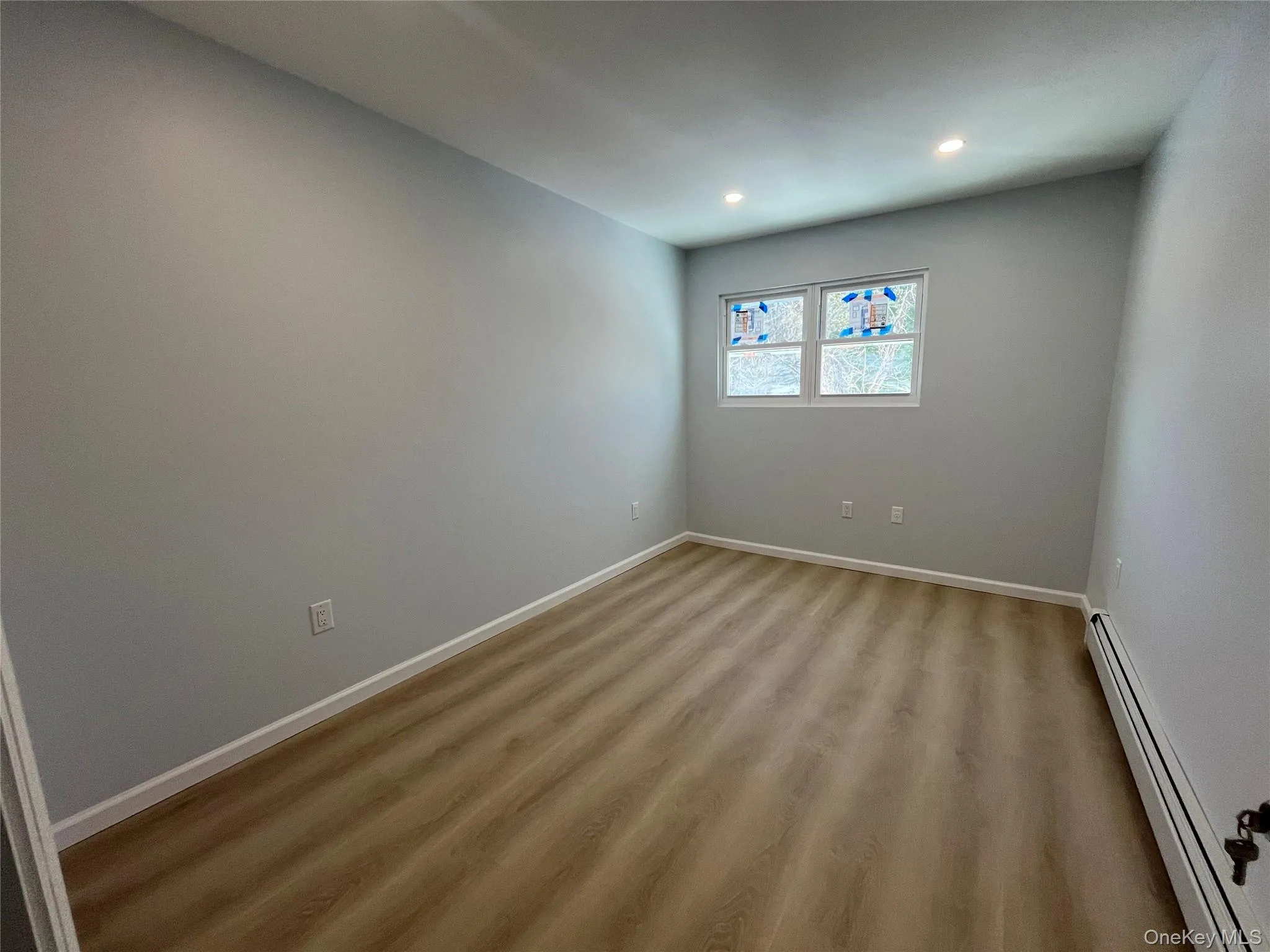 Room featuring a baseboard heating unit, light wood-style floors, and recessed lighting Room featuring a baseboard heating unit, light wood-style floors, and recessed lighting