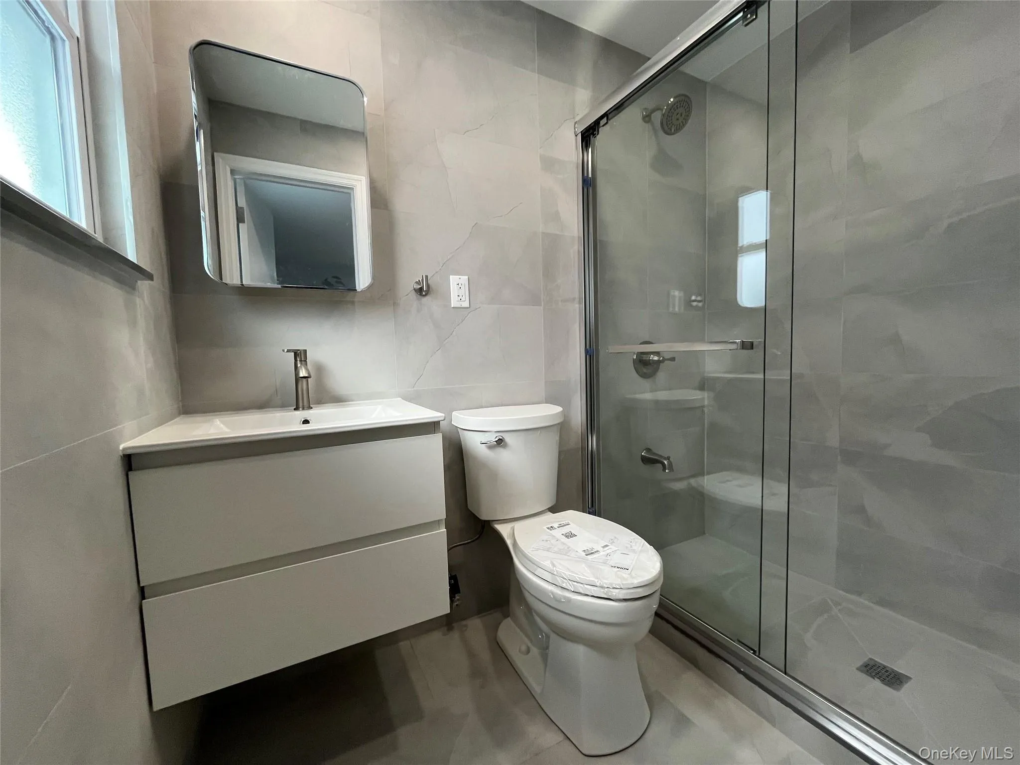 Full bath with tile walls, vanity, and a stall shower Full bath with tile walls, vanity, and a stall shower