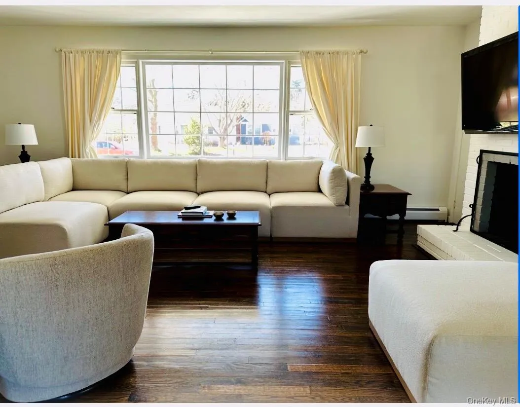 Living area featuring dark wood floors, picture window & fireplace Living area featuring dark wood floors, picture window & fireplace