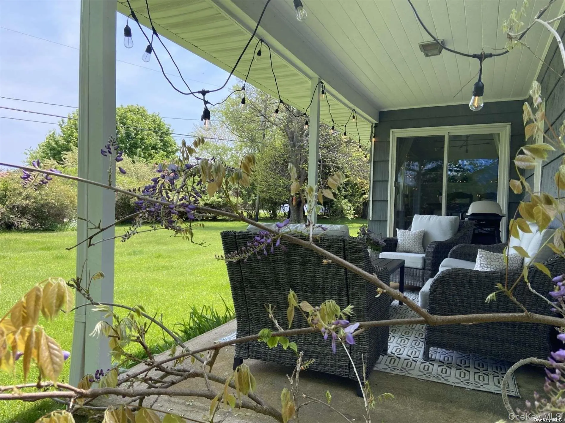 Furnished covered patio with string lights, sliding glass doors, and a concrete surface Furnished covered patio with string lights, sliding glass doors, and a concrete surface