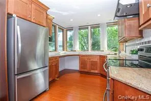 Kitchen with stainless steel appliances, wood finish cabinets, ventilation hood, dark wood finished floors, and recessed lighting Kitchen with stainless steel appliances, wood finish cabinets, ventilation hood, dark wood finished floors, and recessed lighting