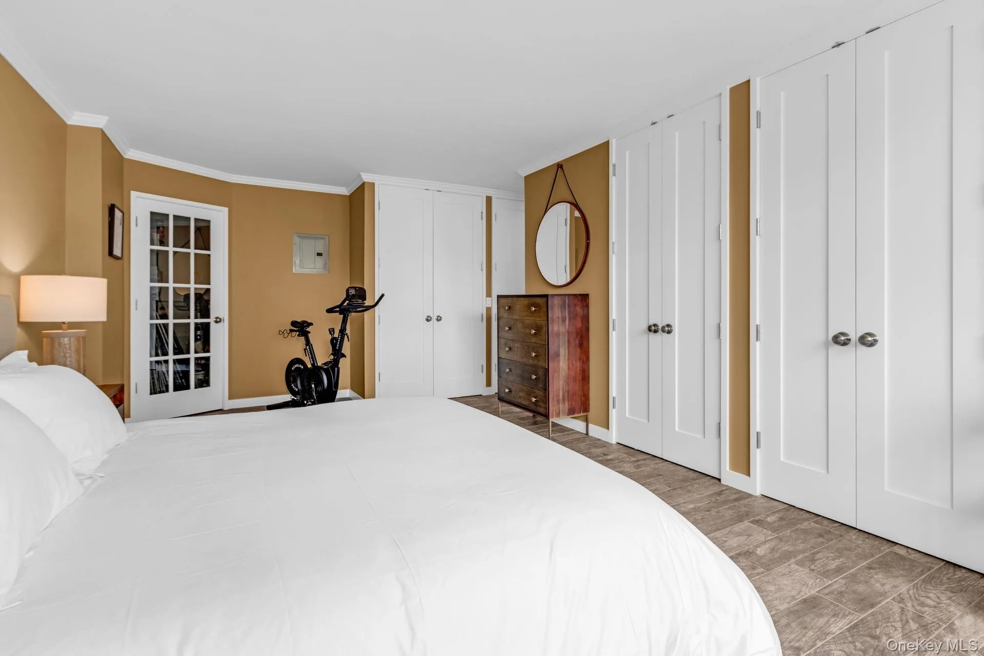 Bedroom with multiple closets, ornamental molding, and wood finished floors Bedroom with multiple closets, ornamental molding, and wood finished floors