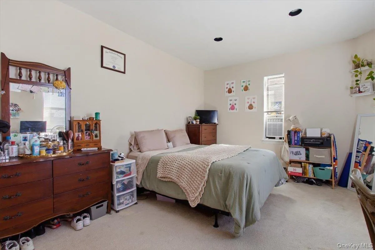 Bedroom featuring light colored carpet and multiple windows Bedroom featuring light colored carpet and multiple windows