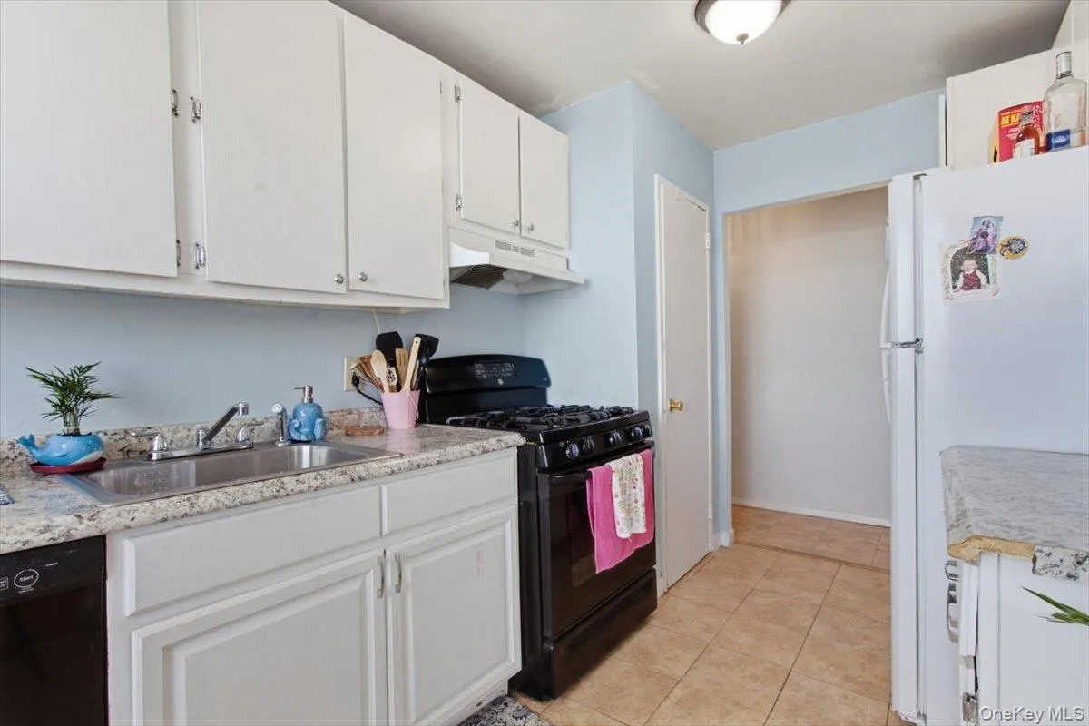 Kitchen featuring black appliances, light countertops, white cabinets, and light tile patterned floors Kitchen featuring black appliances, light countertops, white cabinets, and light tile patterned floors