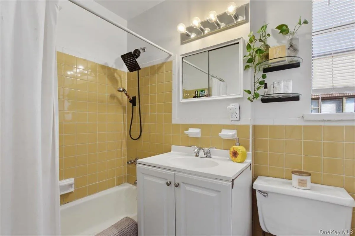Bathroom with vanity, shower / tub combo, and tile walls Bathroom with vanity, shower / tub combo, and tile walls