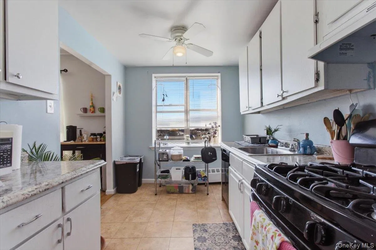 Kitchen featuring black range with gas cooktop, white cabinetry, a ceiling fan, light tile patterned floors, and stainless steel dishwasher Kitchen featuring black range with gas cooktop, white cabinetry, a ceiling fan, light tile patterned floors, and stainless steel dishwasher