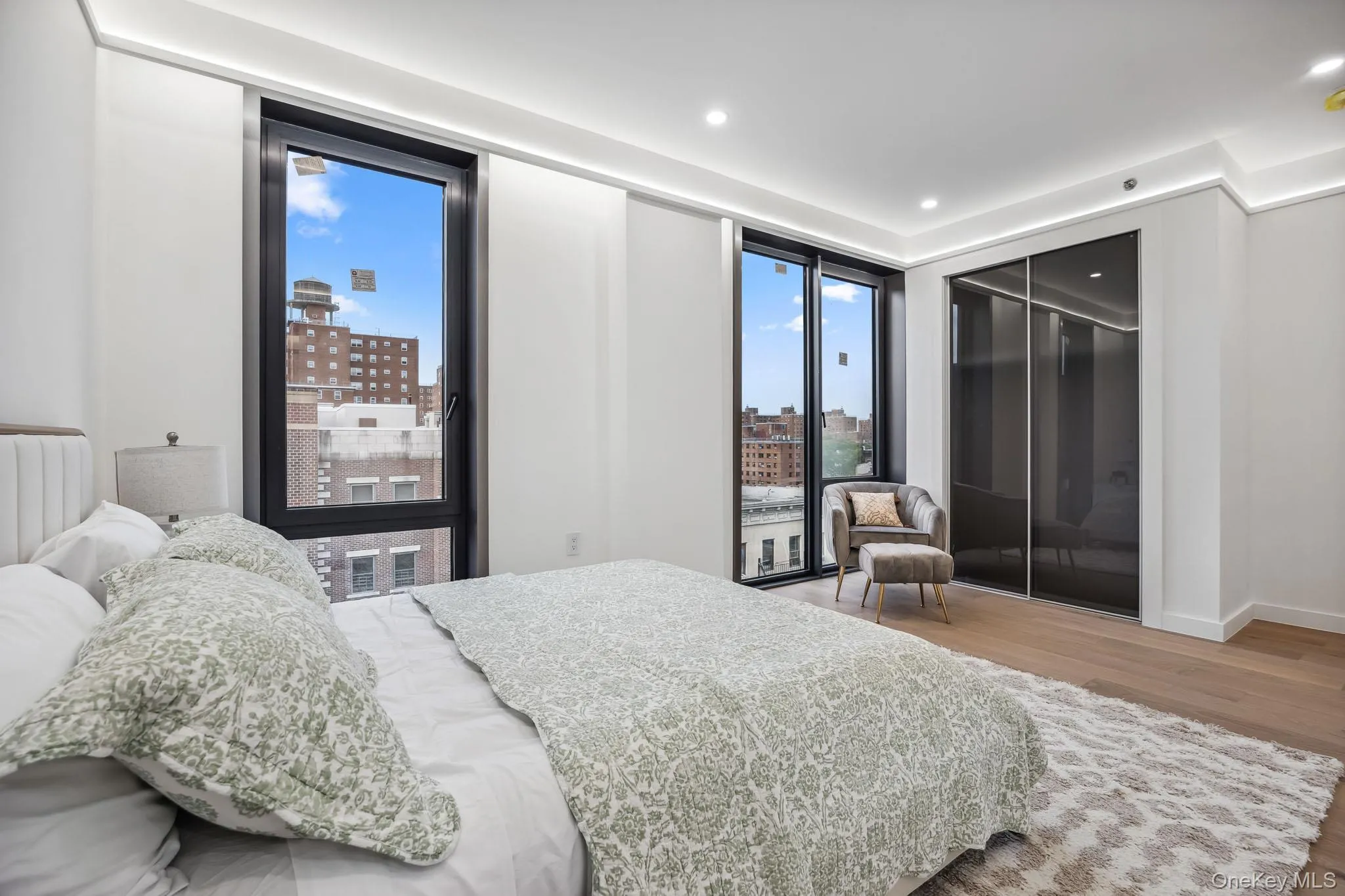 Bedroom featuring wood finished floors, radiator, a city view, recessed lighting, and baseboards Bedroom featuring wood finished floors, radiator, a city view, recessed lighting, and baseboards