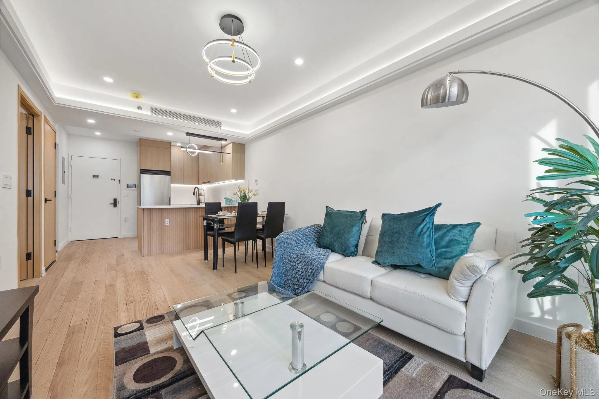 Living room with light wood-style flooring, recessed lighting, a raised ceiling, and a chandelier Living room with light wood-style flooring, recessed lighting, a raised ceiling, and a chandelier
