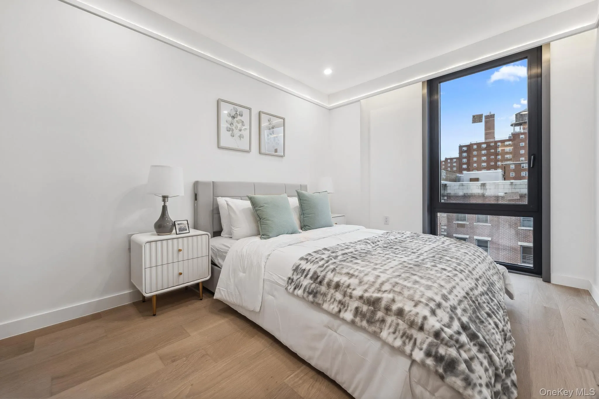 Bedroom featuring light wood-style flooring, baseboards, recessed lighting, and a view of city Bedroom featuring light wood-style flooring, baseboards, recessed lighting, and a view of city