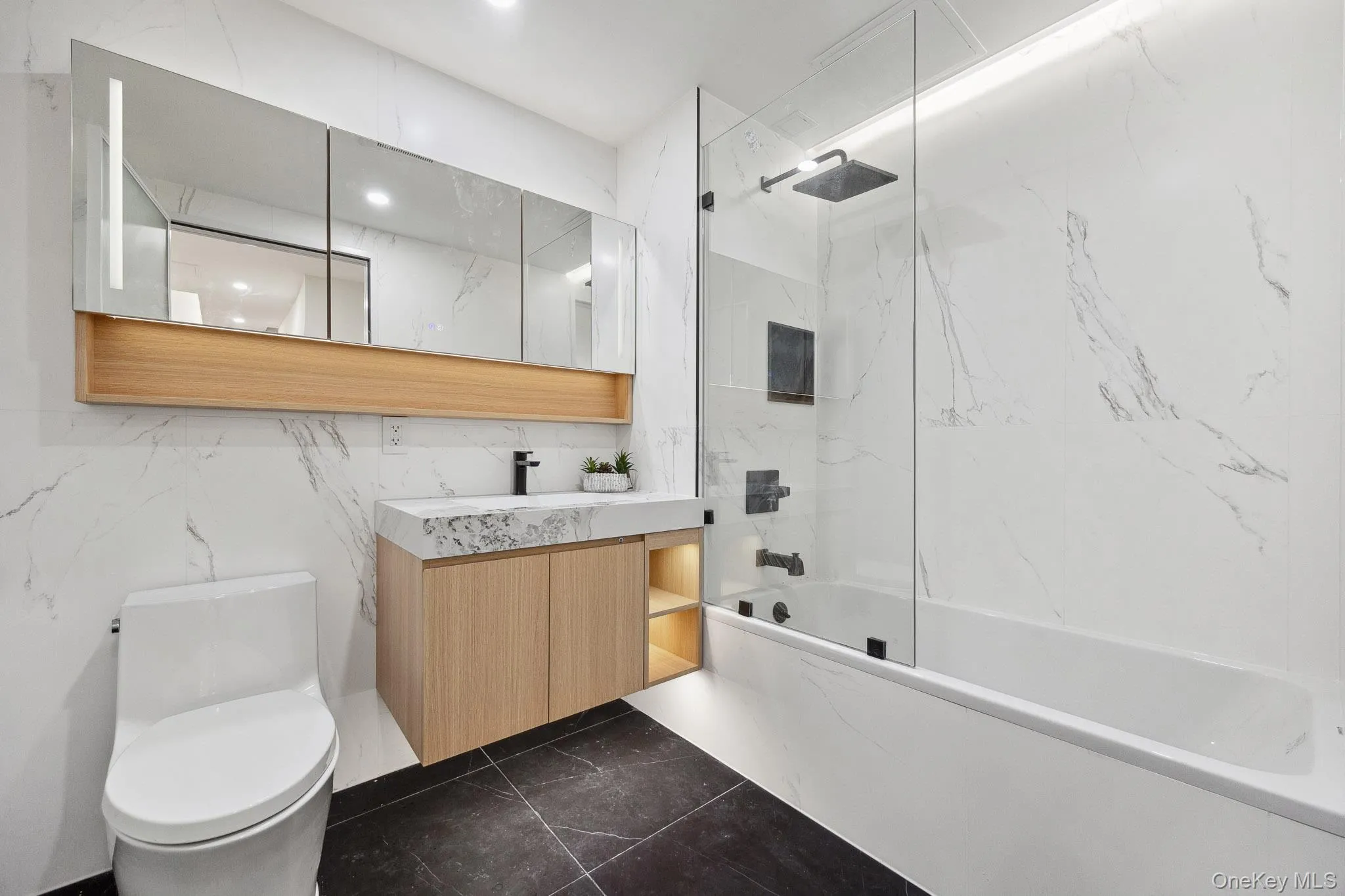 Full bath with toilet, bathing tub / shower combination, vanity, marble finish flooring, and recessed lighting Full bath with toilet, bathing tub / shower combination, vanity, marble finish flooring, and recessed lighting