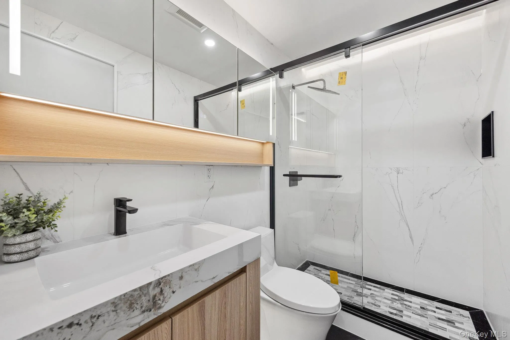Full bath featuring toilet, a marble finish shower, and vanity Full bath featuring toilet, a marble finish shower, and vanity