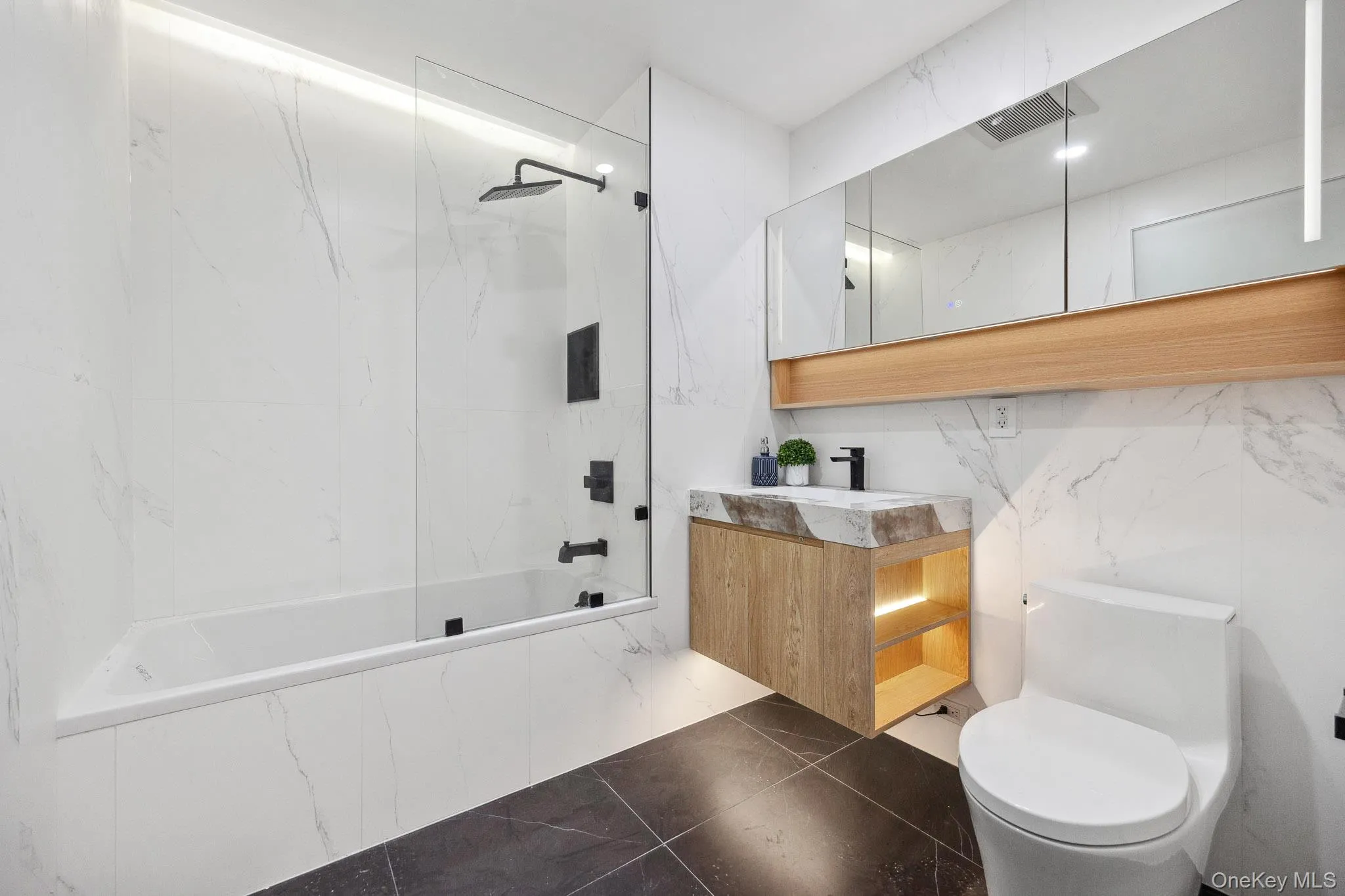 Bathroom with toilet, a combined bath / shower with marble appearance, and vanity Bathroom with toilet, a combined bath / shower with marble appearance, and vanity