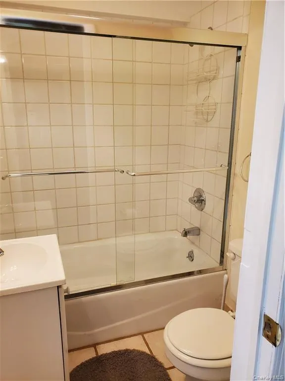 Bathroom featuring toilet, tile patterned floors, combined bath / shower with glass door, and vanity Bathroom featuring toilet, tile patterned floors, combined bath / shower with glass door, and vanity