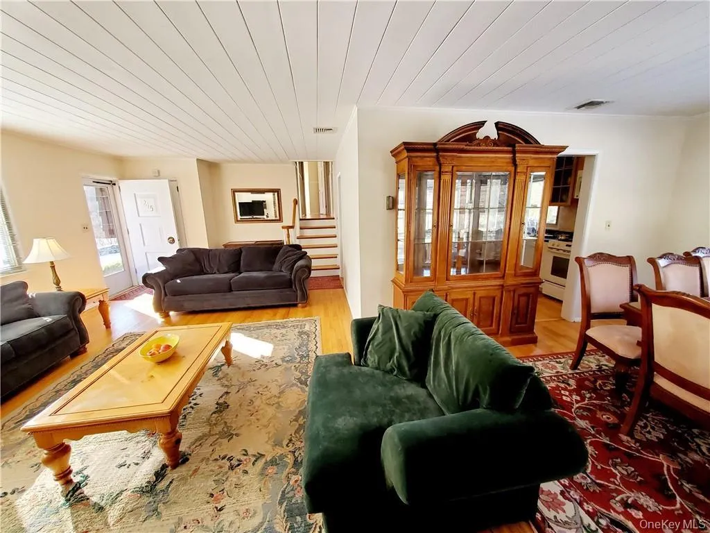 Living room featuring visible vents, stairs, wood finished floors, and wooden ceiling Living room featuring visible vents, stairs, wood finished floors, and wooden ceiling