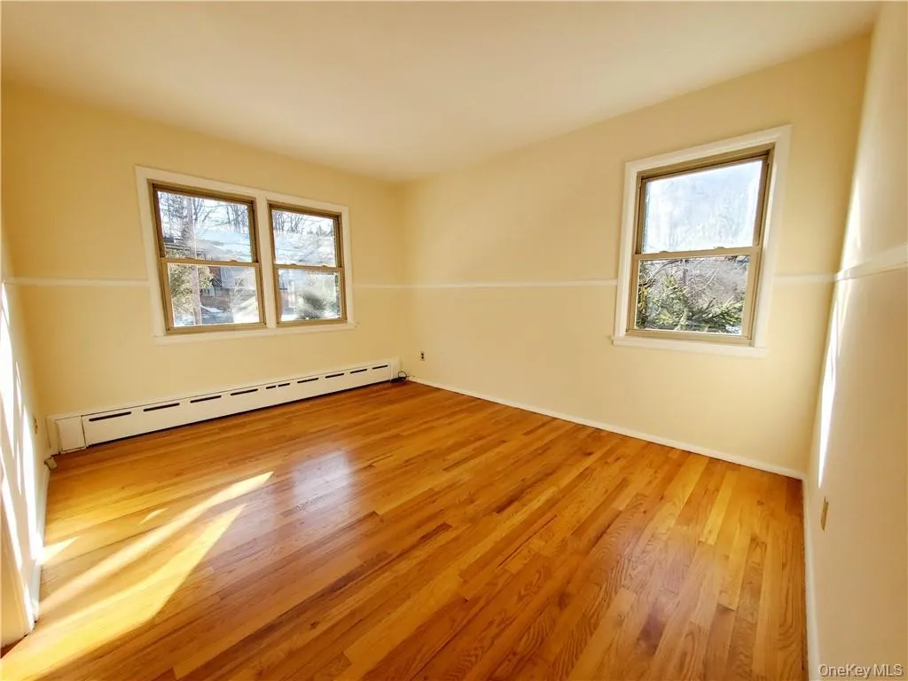 Spare room featuring a healthy amount of sunlight, baseboards, baseboard heating, and wood finished floors Spare room featuring a healthy amount of sunlight, baseboards, baseboard heating, and wood finished floors