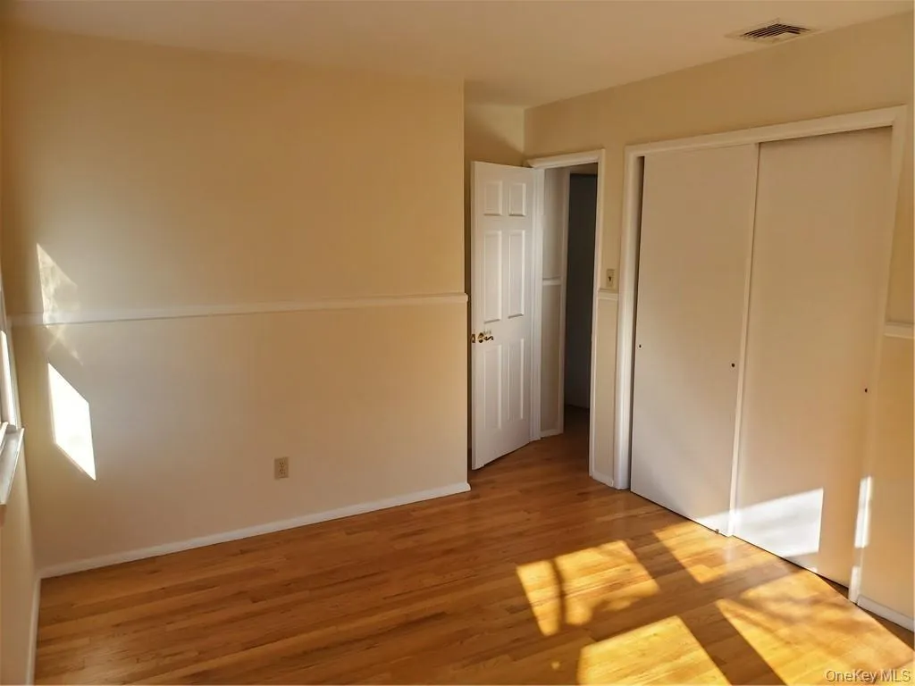 Unfurnished bedroom with visible vents, light wood finished floors, baseboards, and a closet Unfurnished bedroom with visible vents, light wood finished floors, baseboards, and a closet