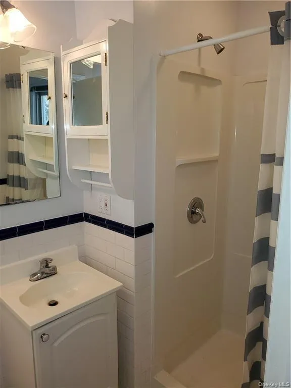 Bathroom with vanity, a shower with curtain, and tile walls Bathroom with vanity, a shower with curtain, and tile walls