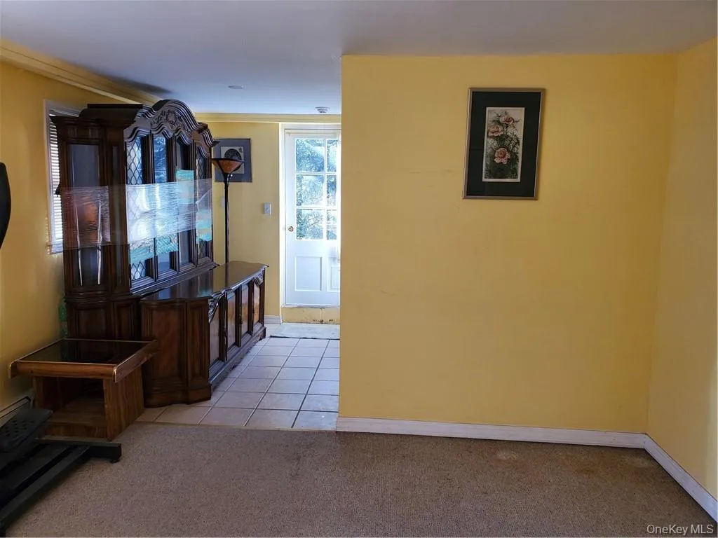 Hallway featuring baseboards, light colored carpet, and light tile patterned floors Hallway featuring baseboards, light colored carpet, and light tile patterned floors