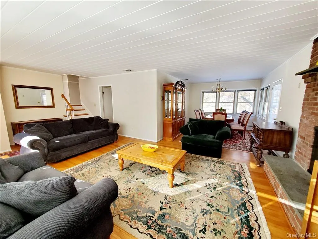 Living room featuring stairs, an inviting chandelier, and light wood finished floors Living room featuring stairs, an inviting chandelier, and light wood finished floors