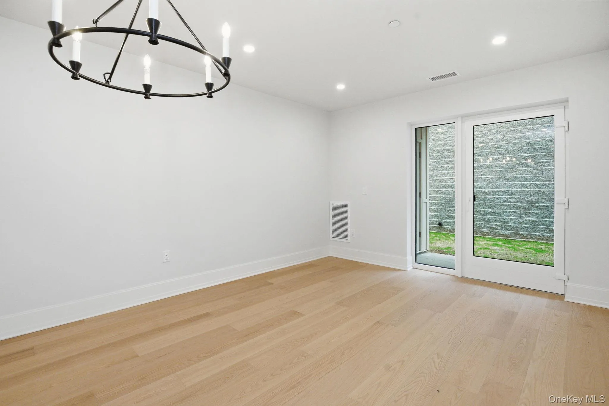 Expansive main living space enhanced by wide-plank flooring, recessed lighting, and direct access to the private patio beyond. Expansive main living space enhanced by wide-plank flooring, recessed lighting, and direct access to the private patio beyond.