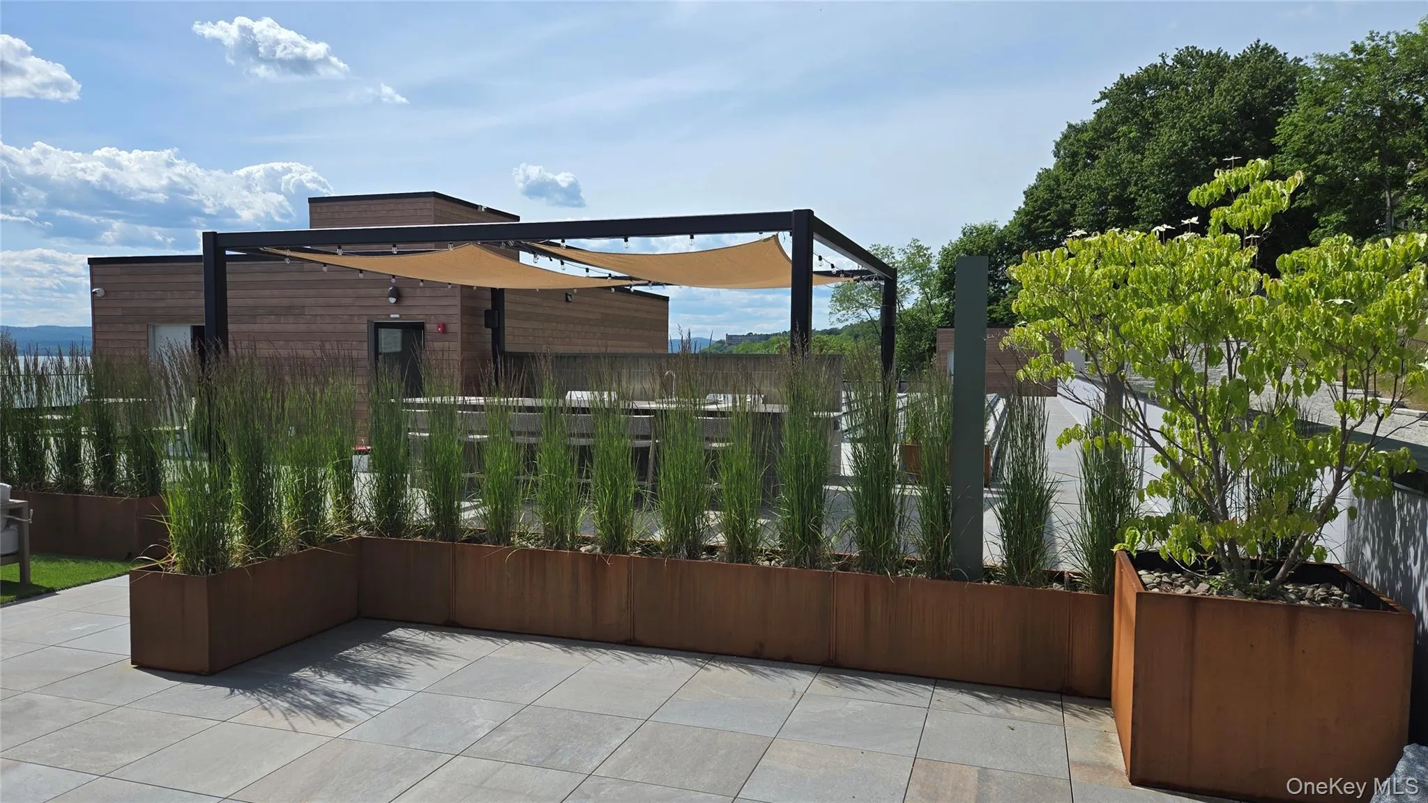 Corten steel planters and tall grasses frame the rooftop's pergola-covered kitchen and bar. Corten steel planters and tall grasses frame the rooftop's pergola-covered kitchen and bar.